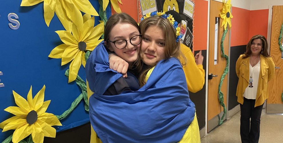 two student hug wrapped in Ukrainian flag